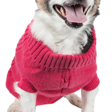 Small black and white dog wearing a bright pink ribbed dog sweater on white background